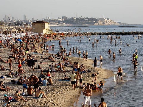 File photo: Beachgoers hang out on the shore of the Mediterranean Sea in Tel Aviv. 