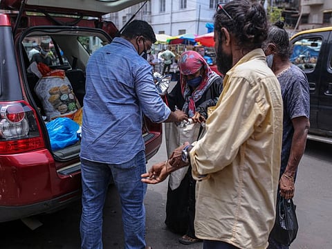 A volunteer for Khana Chahiye, or Want Food collective, distributes free food packs on the street to those in need in Mumbai, India, on July 7, 2021. 