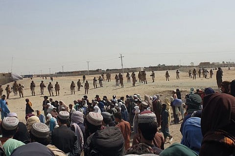 Pakistani border guards cordon off the area as stranded people gather near a border crossing between Afghanistan and Pakistan in Chaman on July 15, 2021. Pakistan border guards used tear gas on July 15 to disperse hundreds of people who tried to storm a border crossing with Afghanistan, a day after the Taliban seized control of the Afghan side of the frontier, officials said. 
