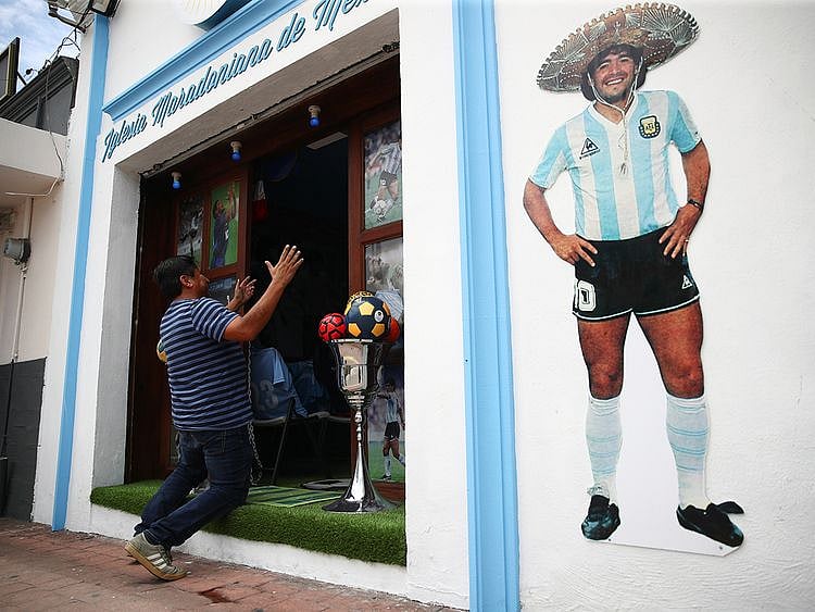 A fan kneels at the entrance to the first Mexico's church in memory of soccer legend Diego Maradona in San Andres Cholula, in Puebla state, Mexico.
