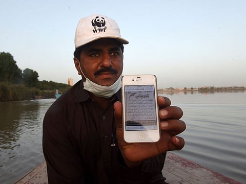 Abdul Jabbar, a member of the World Wildlife Fund (WWF) dolphin rescue team, shows an awareness message written in Urdu for the community to protect and conserve endangered Indus river dolphins, during a monitoring routine along the Indus river near Pakistan's southern Sindh province city of Sukkur.  