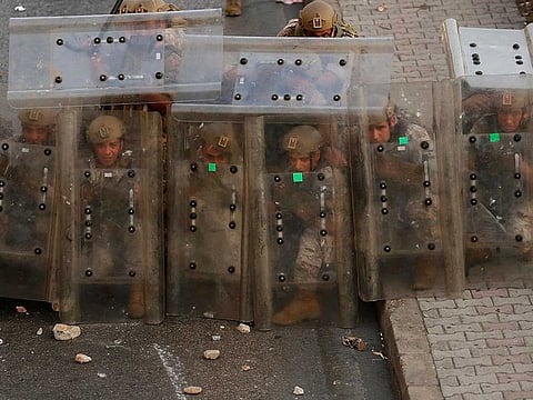 Lebanese soldiers hide from stones behind their protective shields as they clash with supporters of Prime Minister-designate Saad Hariri who stepped down on Thursday in Beirut, Lebanon, Thursday, July 15, 2021. 