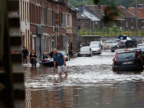 Residents wade through flood water on a flooded street in Angleur near Liege, Belgium, on Friday, July 16, 2021. In Liege, one of Belgium’s largest cities, people have been asked to evacuate homes in the city centre as devastating floods also swamped parts of western Germany, Luxembourg, and the Netherlands.  