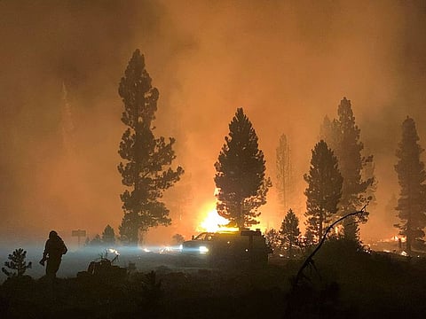 This handout photo obtained July 18, 2021 courtesy of the US Forest Service shows a firefighter and rig during night operations on the night of July 17 and early morning of July 18, 2021 at the Bootleg Fire, near Klamath Falls, Oregon.