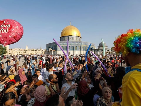 A man in a clown costume entertains Palestinians and their children as they celebrate alongside Muslims worldwide the first day of Eid Al Adha feast, at Al Aqsa Mosque complex in Jerusalem's old city, on July 20, 2021.  