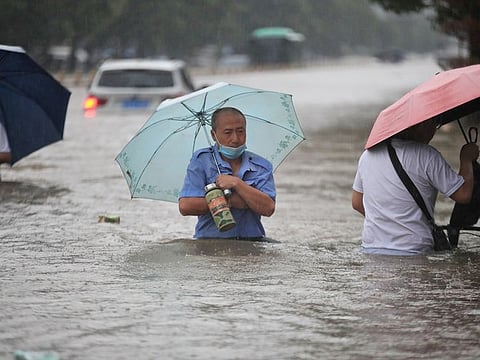 Residents wade through floodwaters on a flooded road amid heavy rainfall in Zhengzhou, Henan province, China July 20, 2021.