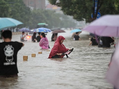 Residents wade through floodwaters on a flooded road amid heavy rainfall in Zhengzhou, Henan province, China on July 20, 2021.  