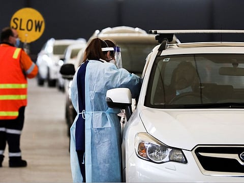 A health worker collects swab samples from a resident at a Covid-19 drive-through testing facility in Melbourne on July 16, 2021, after Australia's second largest city entered a fresh lockdown amid a resurgence in coronavirus cases. 