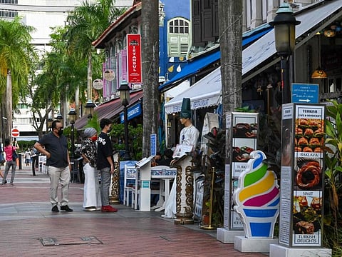 People browse a menu at the entrance to a restaurant serving Turkish cuisine in the Arab Street district of Singapore on July 20, 2021. Singapore recorded 162 new locally-transmitted COVID-19 cases on Thursday, close to an 11-month high from earlier this week. 