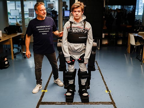 Jean-Louis Constanza, Chief Business and Clinical Officer at French company Wandercraft helps his 16-year-old son Oscar using a robot exoskeleton at the company headquarters in Paris. 