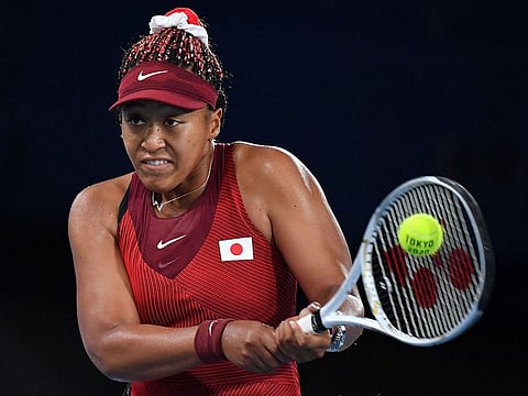 Japan's Naomi Osaka returns the ball to Czech Republic's Marketa Vondrousova during their Tokyo 2020 Olympic Games women's singles third round tennis match at the Ariake Tennis Park in Tokyo.