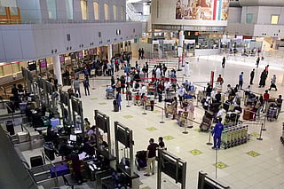 Passengers queue at the check-in counters prior to their departure at Kuwait International Airport. 