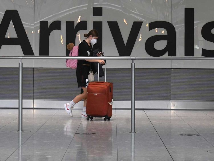 In this file photo taken on June 03, 2021 a pasenger pulls her roller suitcase on arrival in Terminal 5 at Heathrow airport in London, on June 3, 2021. 