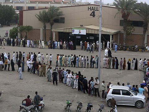 Hundreds of people line up and wait their turn to receive a dose of vaccine at an Expo or convention centre, in Karachi on July 30, 2021. 
