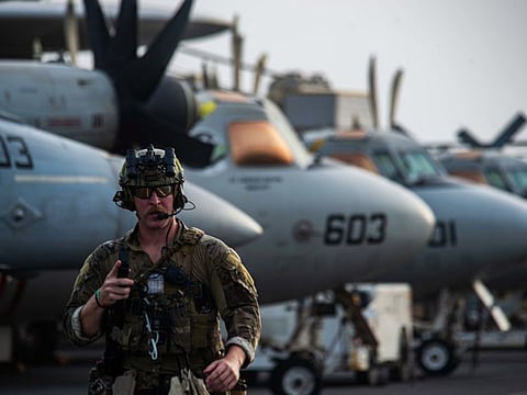 Explosive Ordnance Disposal Technician 3rd Class Ethan Tews walks across the flight deck of aircraft carrier USS Ronald Reagan to board an MH-60S Sea Hawk helicopter to head to an oil tanker that was attacked off the coast of Oman in the Arabian Sea on Friday, July 30, 2021. An attack on an oil tanker linked to an Israeli billionaire killed two crew members off Oman in the Arabian Sea, authorities said Friday, marking the first fatalities after years of assaults targeting shipping in the region. 