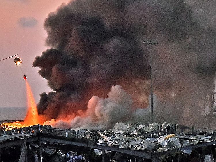 In this photo taken on August 04, 2020 a helicopter puts out a fire at the scene of an explosion at the port of Lebanon's capital Beirut. 