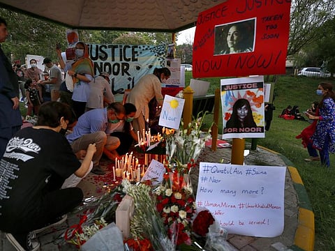 Women’s rights activists place candles and flowers beside posters with the pictures of Noor Mukadam, who was recently brutally beheaded by her childhood friend, during a candle light vigil to pay tribute to Noor and other domestic violence victims, in Islamabad, on July 25, 2021.