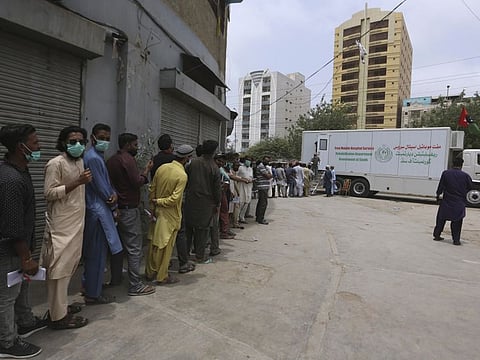 People line up in front a mobile vaccination van to receive a shot of the Sinovac COVID-19 vaccine, in Karachi, on August 6, 2021. 