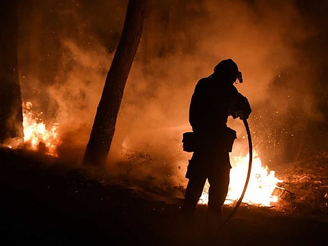 A firefighter battles a wildfire burning in the suburb of Thrakomakedones, north of Athens, Greece, August 7, 2021. 