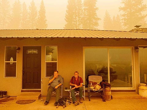 Gould Fickardt, 72, (L) talks with Woody Holland, 70, (R) about their burned homes in Greenville, California on August 7, 2021. Fickhardt owned an apartment building and the town bar in Greenville, both of which burned down during the Dixie fire. The Dixie Fire has now ravaged 446,723 acres in four counties. 