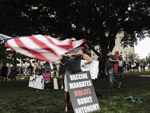 A demonstrator waves an American flag during a protest against vaccination mandates in Lansing, Michigan, US, on August 6, 2021. 