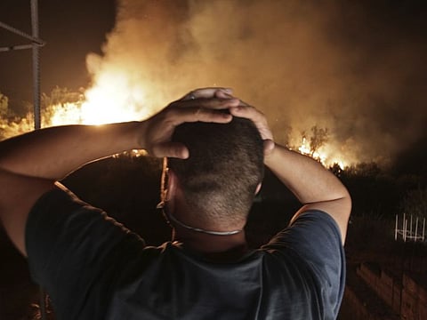 A man looks at a forest fire near the village of Larbaa Nath Irathen, neat Tizi Ouzou, in the mountainous Kabyle region, 100 kilometres (60 miles) east of Algeria's capital of Algiers on August 12, 2021. 