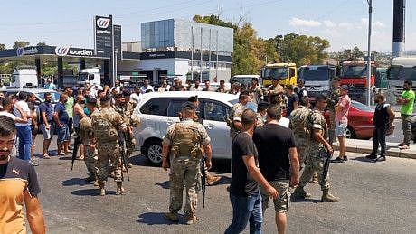 Lebanese soldiers try to open a road blocked by cars near a petrol station in Sidon on August 12, 2021. 