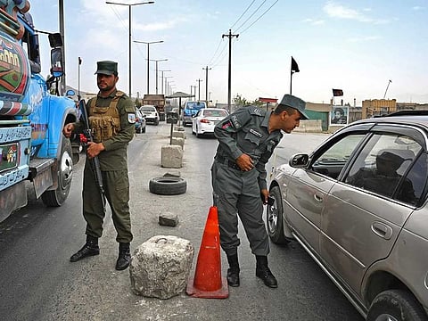 Afghan policemen stand guard at a checkpoint along the road in Kabul on August 14, 2021. 