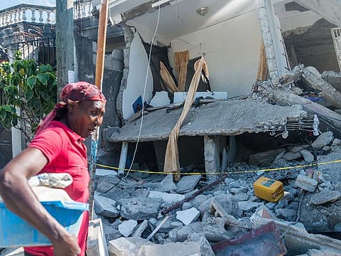 A Haitian woman cries as she passes a  destroyed house in Les Cayes on August 15, 2021, after a 7.2-magnitude earthquake struck the southwest peninsula of the country. 