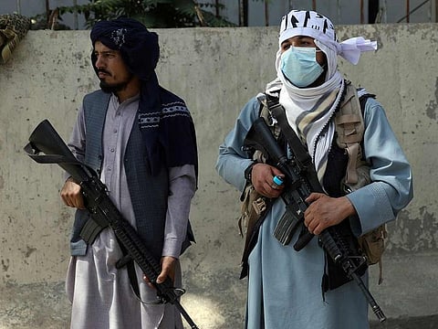 Taliban fighters stand guard in the main gate leading to Afghan presidential palace, in Kabul, Afghanistan, Monday, Aug. 16, 2021.