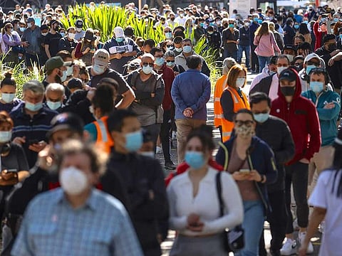 People wearing face masks stand in a line as they wait to be vaccinated at the Sydney Olympic Park Vaccination Centre at Homebush in Sydney on August 16, 2021.