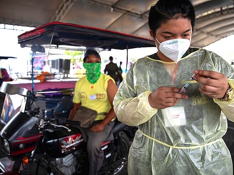 A health worker prepares to vaccinate a public transport driver in Quezon City, Metro Manila.
