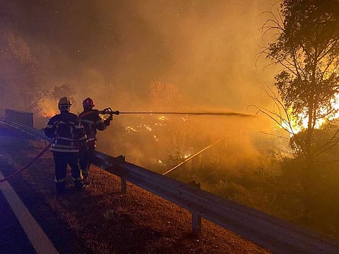 This handout photograph released by Securite Civile on August 17, 2021, shows firefightes from Savoie SDIS73 as they use a hose to fight a fire in the hills at Gonfaron, south-eastern France late August 16. 