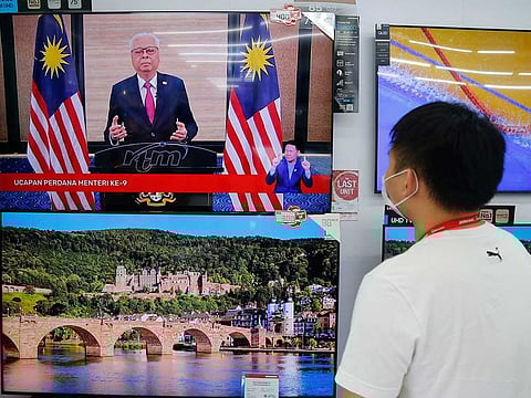 An electronic shop worker watches a speech by Malaysia's new Prime Minister Ismail Sabri Yaakob on television in Shah Alam, Malaysia, Sunday, Aug. 22, 2021. Ismail struck a conciliatory tone in his first national address Sunday, saying he would embrace the opposition in efforts to tackle a runaway pandemic and revive a slumping economy. 