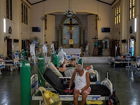 Patients sit in beds after being admitted in the chapel of Quezon City General Hospital turned into a COVID-19 ward amid rising infections