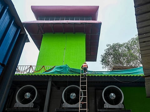 A worker climbs up a ladder at the 25-metre (82-foot) high smog tower, built to purify the air during pollution season, in New Delhi on August 23, 2021. (Photo by Money SHARMA / AFP)