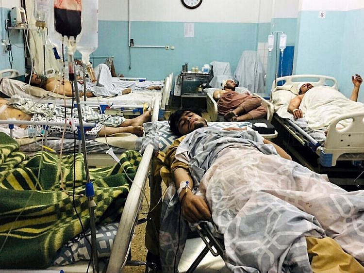 Wounded Afghans lie on a bed at a hospital after a deadly explosion