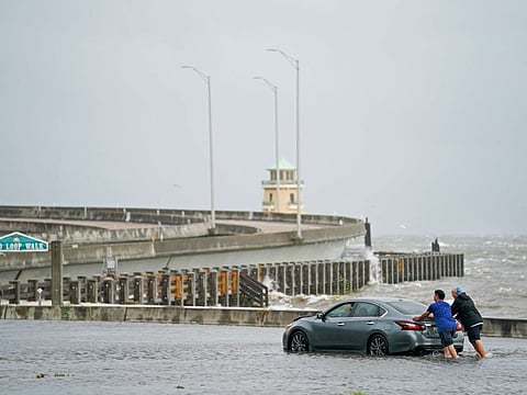 Two men help a stranded motorist in floodwaters on Beach Blvd. on August 30, 2021 in Biloxi, Mississippi. 