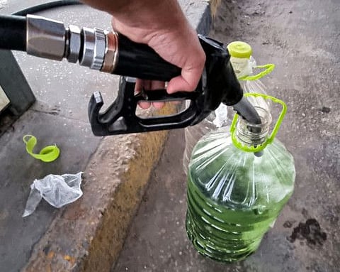 A man loads up plastic water containers with gasoline at a petrol station in Libya's capital Tripoli on August 26, 2021.  Algeria stopped providing leaded petrol last month, prompting the UN Environment Agency to declare the “official end’’ of its use in cars, which has been blamed for a wide range of human health problems. 