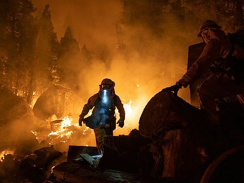 Firefighters attempt to protect a home near Santa Claus Drive during the Caldor Fire near Meyers, California. 