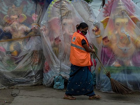A sanitation worker sweeps the area where idols of Ganesha are displayed for sale ahead of the festival on the outskirts of Hyderabad on September 7, 2021. 