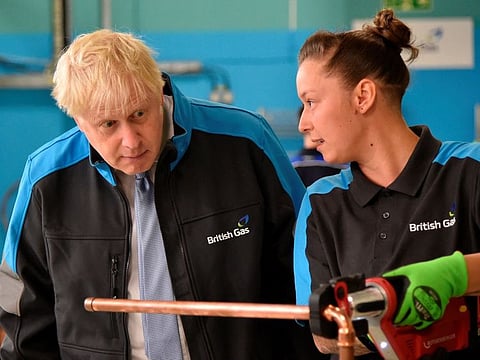 Britain's Prime Minister Boris Johnson listens to apprentice Amy Gray during a visit to a British Gas training academy near Leicester, central England on September 13, 2021.  Expanded vaccinations are expected to be part of a “tool kit’’ to control COVID-19 infections this fall and winter that Prime Minister Boris Johnson plans to announce on Tuesday at a news conference.