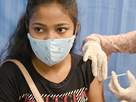A health worker inoculates a woman with a dose of Covaxin COVID-19 vaccine at a temporary vaccination centre set up inside a school in Mumbai. 