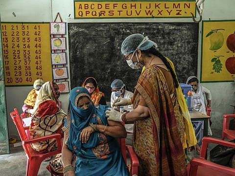 A woman winces as she receives a COVID-19 vaccination in Mohammadpur Kadeen, a village in the state of Uttar Pradesh, India, in a file photo.. 