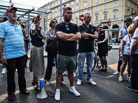 People hold a silent protest against the so-called Green Pass vaccination passport outside the Porta Nuova railway station in Turin.  