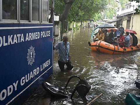 Police officials and their family members travel in a boat through the waterlogged area to reach the gate of a city police quarters in Kolkata on September 22, 2021, following a heavy rainfall. 