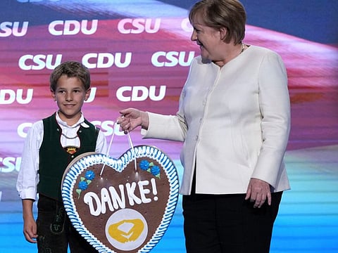 A young Bavarian boy in traditional clothes hands over a gingerbread heart reading "Thanks" to German chancellor Angela Merkel during a state election campaign in Munich, on September 24, 2021.