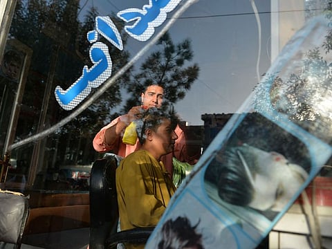 In this picture taken on September 19, 2021, 24-year-old Nader Shah attends a customer at his barber shop in Herat.  