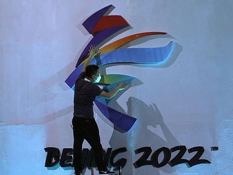 A man adjusts an emblem of the Beijing 2022 Winter Olympic Games before a ceremony unveiling the slogan, in Beijing, China.