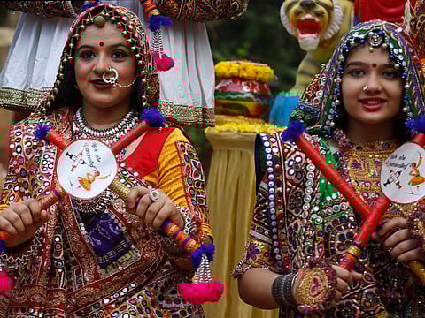 Indians wearing traditional attire and holding dandiya with sticker pasted on it that “we are vaccinated” pose for photograph before practice Garba, the traditional dance of Gujarat state, ahead of Navratri festival in Ahmedabad, India, on October 1, 2021. 